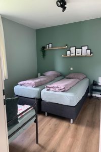 Slaapkamerinspiratie: logeerkamer met groene muren in twee kleuren en warm roze beddengoed.met