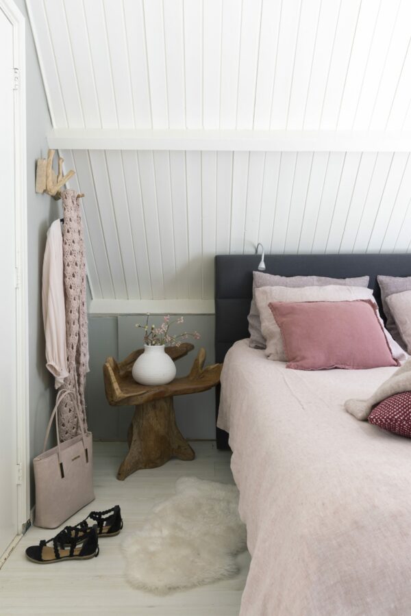 Slaapkamerinspiratie: masterbedroom met houten boomstamkrukje en linnen beddengoed in roze.